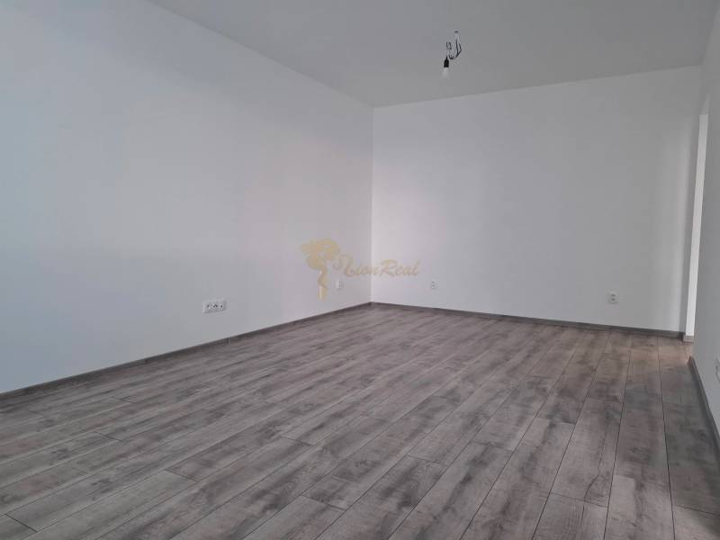 An empty room with a wood-patterned floor in a three-room apartment, white walls.