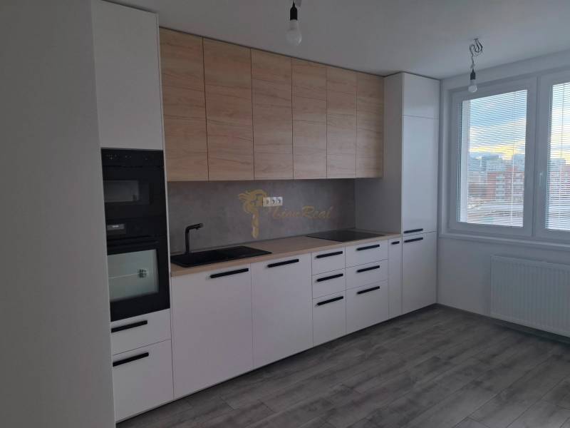 A kitchen in a 3-room apartment with a wooden decor floor and large windows.
