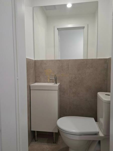 Bathroom in a 3-room apartment with a sink and toilet, neutral-colored tiles.
