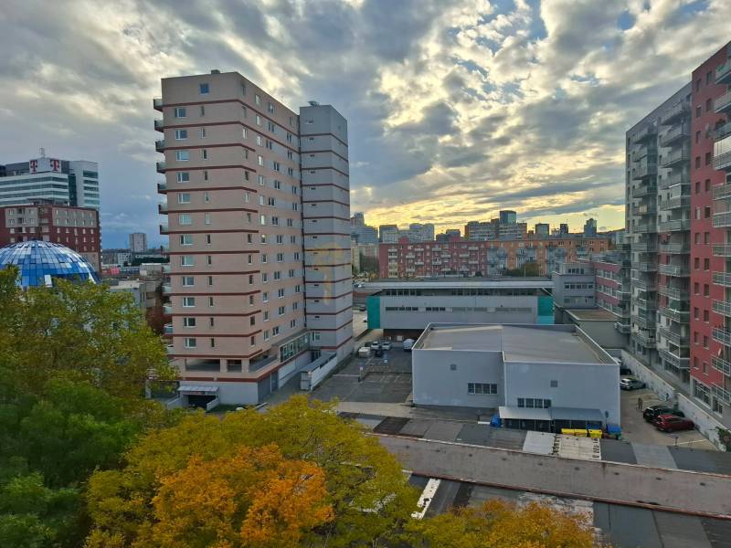 A view of buildings and the sky in Bratislava – Ružinov with autumn trees.