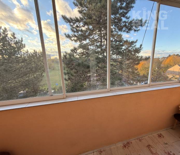 View from a 3-room apartment on MDŽ 1848/33 Street in Šurany, with a glazed balcony and trees.