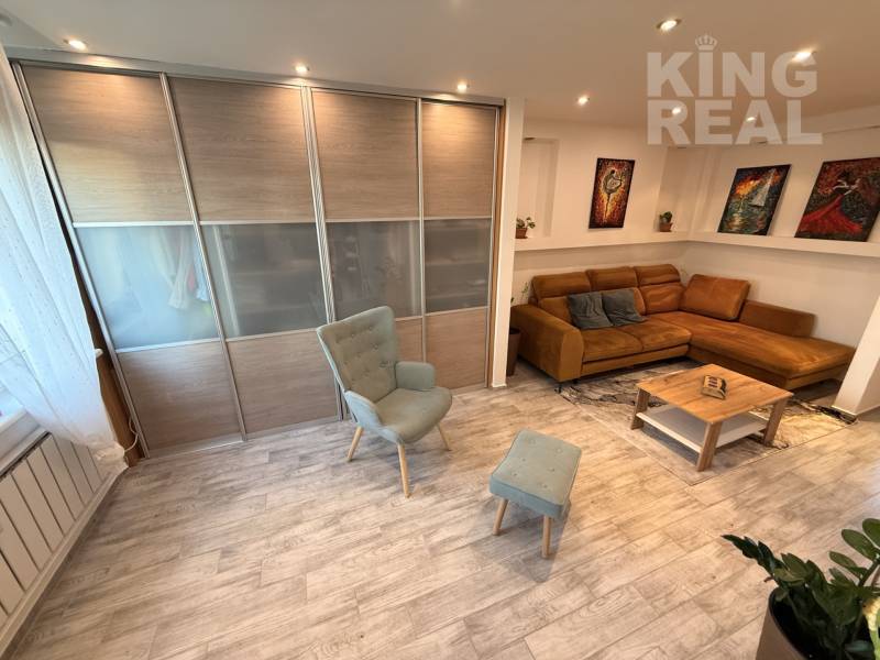 Living room with a sofa, an armchair, and a wooden decor floor in a 3-room apartment.