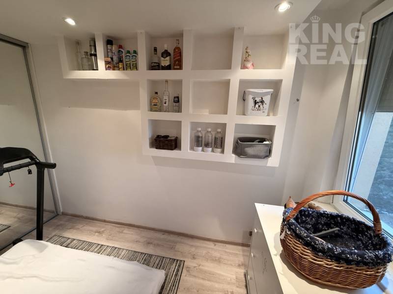 A room in a 3-room apartment with shelves, a treadmill, and a floor with a wooden decor.