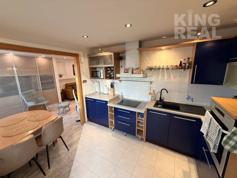 A kitchen in a 3-room apartment with a blue kitchen unit and a dining table.