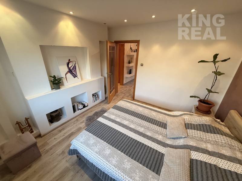 A bedroom in a 3-room apartment with a wood-patterned floor and wall decorations.