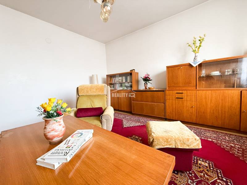 Living room in a family house with wooden furniture, a carpet, and a comfortable armchair.