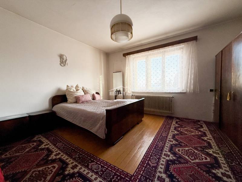 Bedroom with carpet, bed, and wood-patterned flooring in a family house.