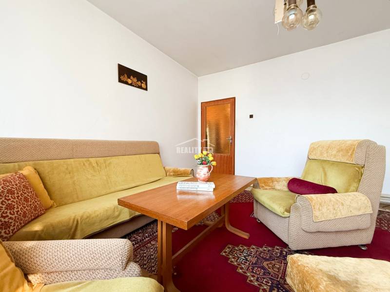 Living room in a family house with a sofa, armchair, table, and decorative cushions.