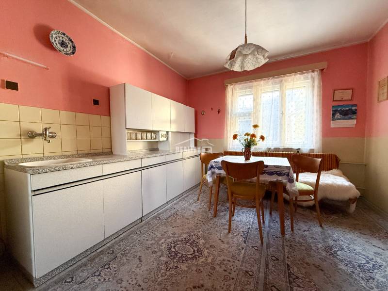 A kitchen in a family house with pink walls, retro furniture, and floral decorations.