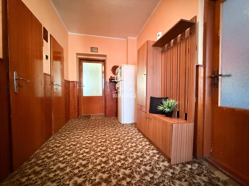 A hallway of a family house with carpet, wooden paneling, and built-in furniture.