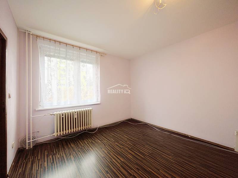 A room in a 3-room apartment with a wooden decor floor and a large window.