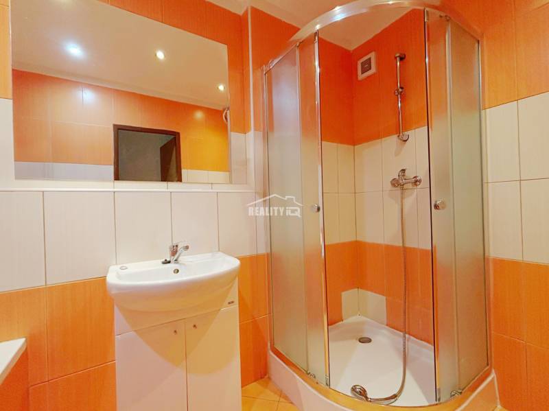 A bathroom with a shower and orange tiles in a 3-room apartment.