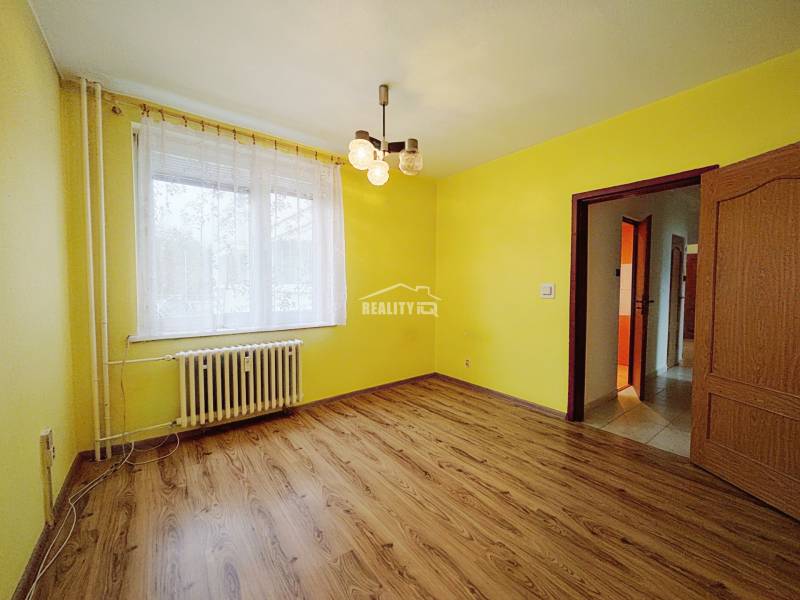 Yellow walls and a wooden decor floor in a 3-room apartment with a radiator.