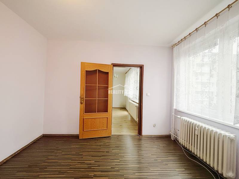 A room in a 3-room apartment with a wooden decor floor and a large window.