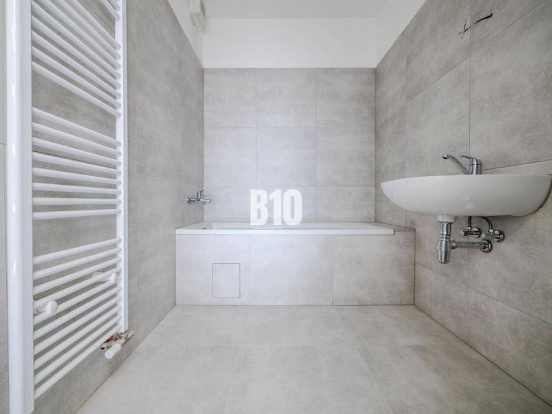 Bathroom with a bathtub and sink in a 3-room apartment, gray tiles, white radiator.