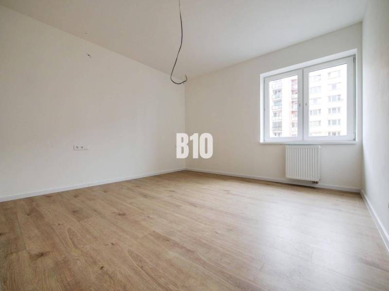 Empty room with wooden floor, white walls, and a window.