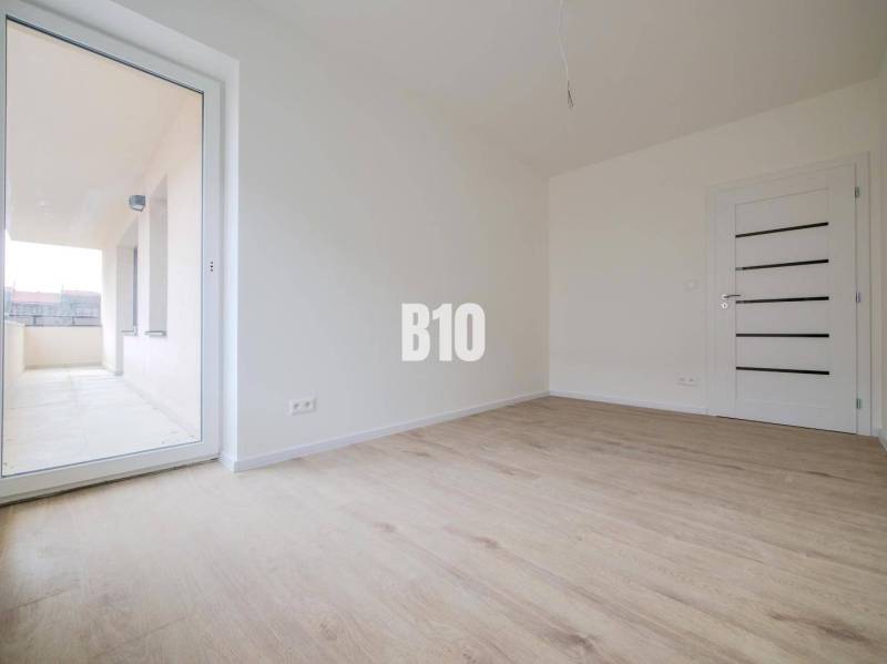Spacious living area with a large window, wooden floors, and a 3-room apartment.