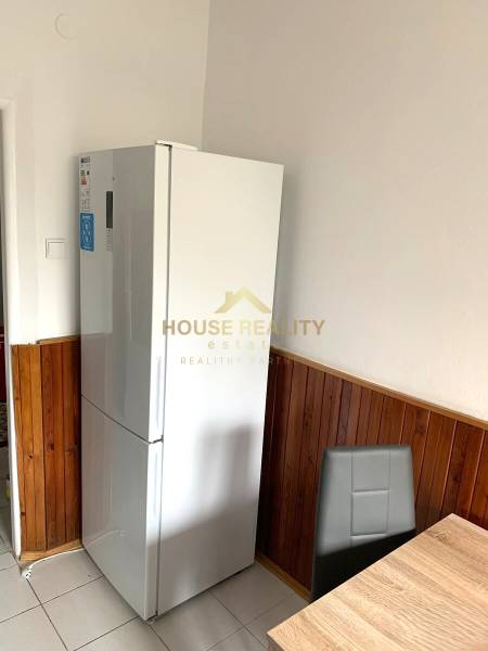 A kitchen with a refrigerator and wooden paneling in a 2-room apartment.