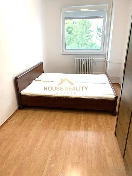Bedroom in a 2-room apartment with wooden decor and a large window.