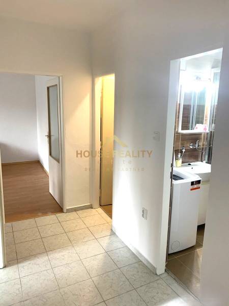 A hallway with ceramic tiles and a wooden decor floor in a 2-room apartment.