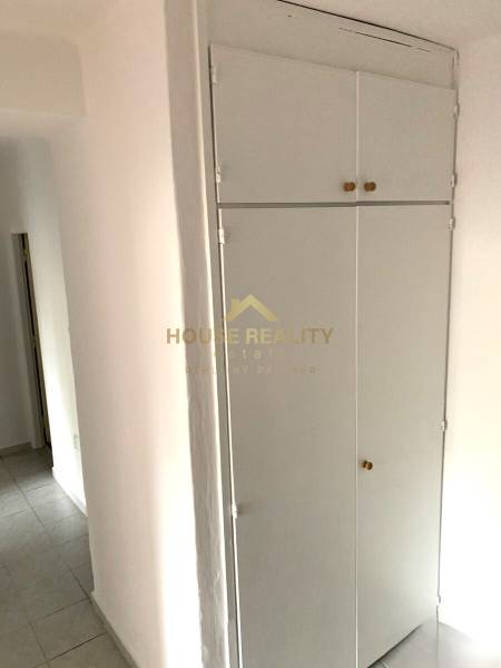 White built-in wardrobe in the hallway of a 2-room apartment with a tiled floor.