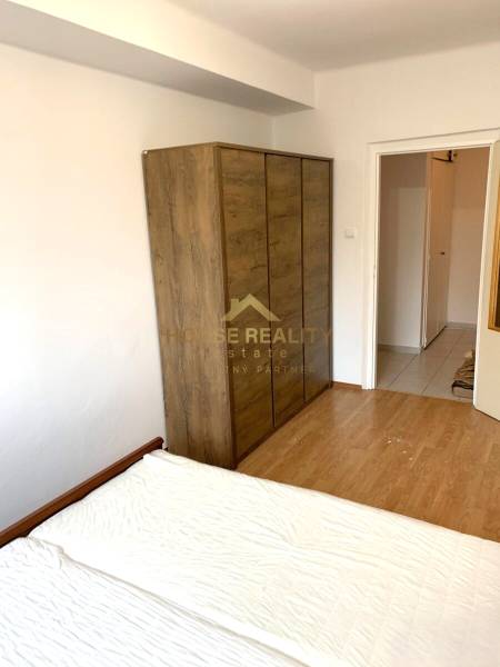 Bedroom with a bed, wardrobe, and wooden decor flooring in a 2-room apartment.