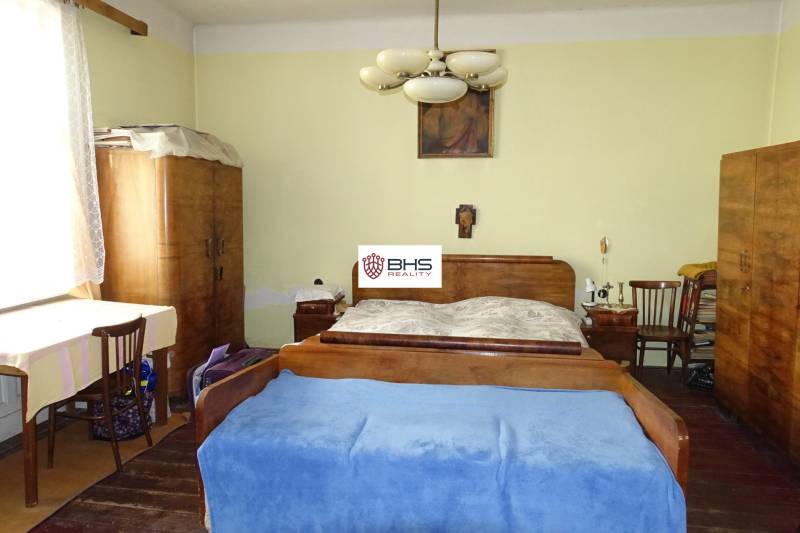 Bedroom in a family house with antique furniture, chandelier, painting, and wooden decor flooring.