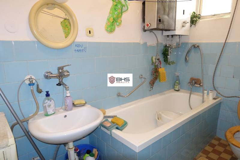 A bathroom with blue tiles and a white bathtub in a family house.
