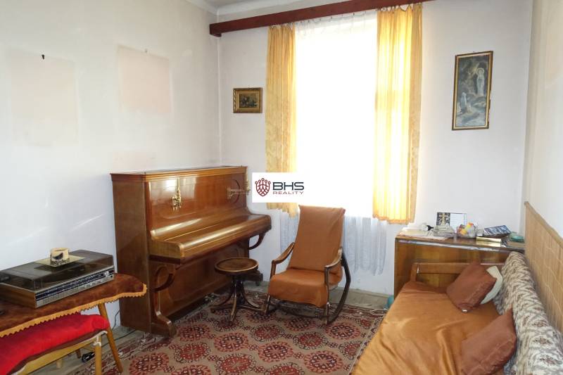 Living room with a piano, armchair, sofa, and a carpet with a red pattern in a family house.
