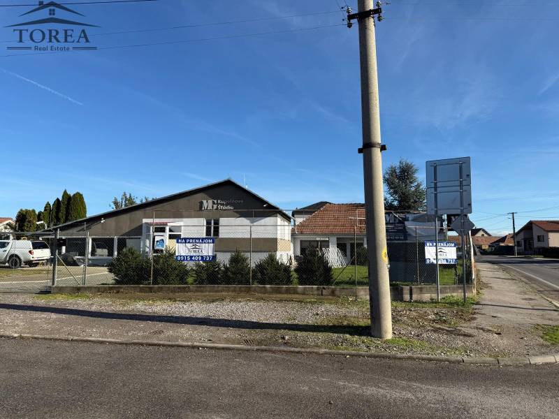 Commercial premises in Dolné Chlebany with parked cars and fencing.
