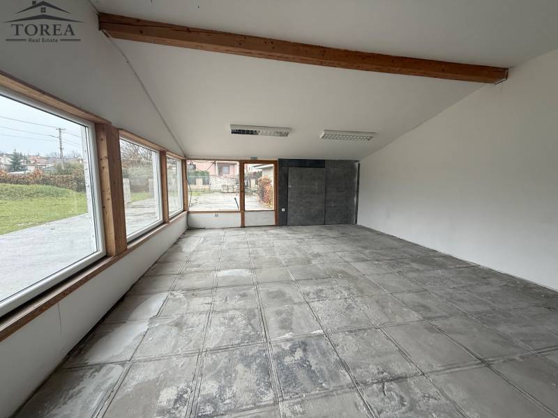 Open space in commercial premises with large windows and concrete floor.
