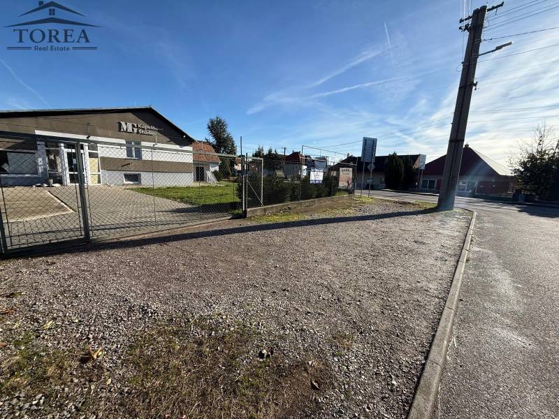 Commercial premises in Dolné Chlebany, fencing, paved area, and asphalt road.