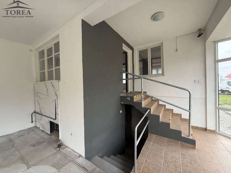 Interior of commercial premises with tiles and stairs, railing leading to a lower floor.