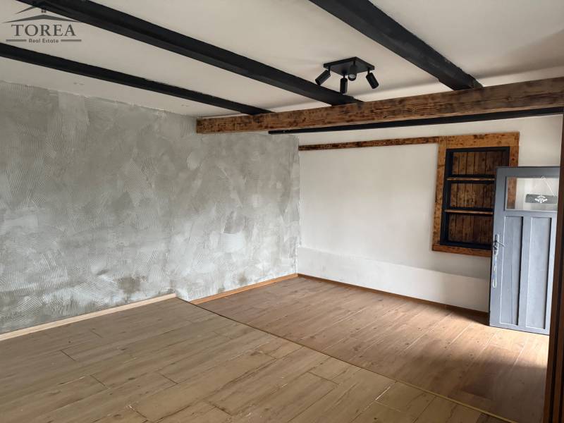 Interior of a commercial space with a wood-patterned floor and prominent beams on the ceiling.