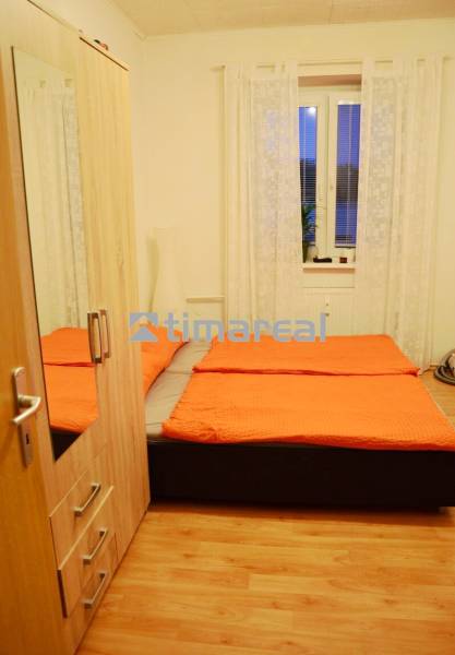 A bedroom with a bed, a wardrobe, and a wooden decor floor in a two-room apartment.