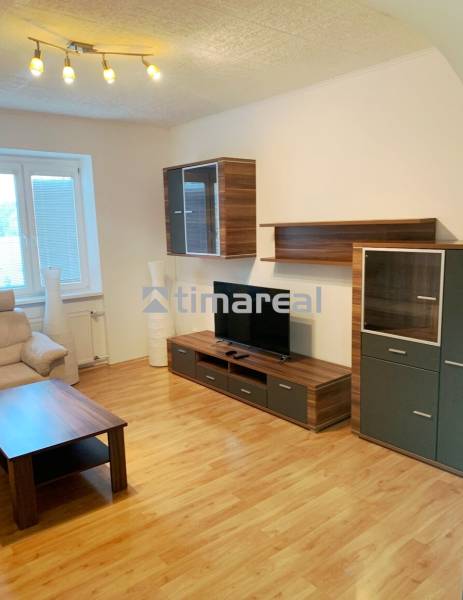 Living room in a two-room apartment with a wooden decor floor and wooden furniture.