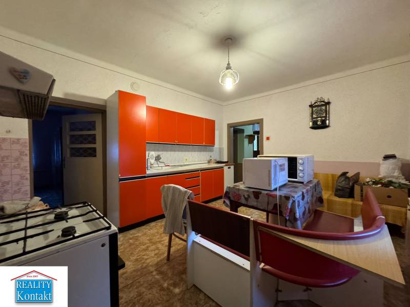 A kitchen in a family house with a red kitchen unit and a table with microwave ovens.