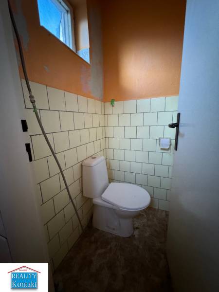 A toilet in a family house with an orange wall and tiles.