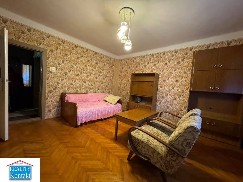 Living room in a family house, floral wallpaper, wooden decor flooring, wooden furniture.