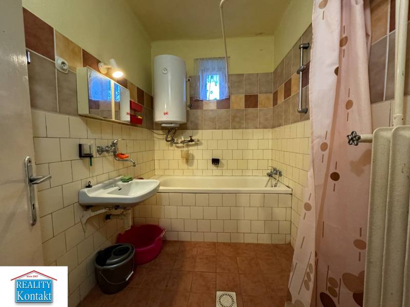 A bathroom in a family house with older sanitary fixtures, tiles, and a shower curtain.