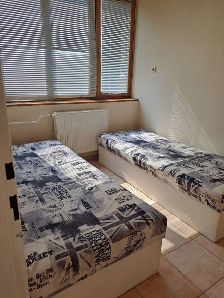 A room with two beds and blinds in a studio apartment, decor with English motifs.