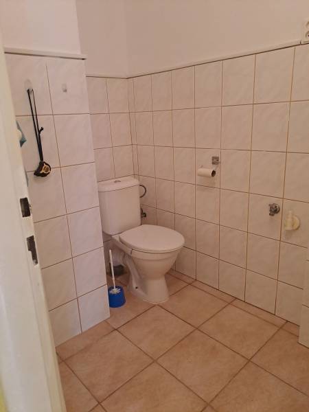 Bathroom in a studio apartment with tiles and a standard toilet.