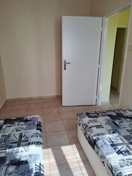 A room with ceramic tiles, a bed with a print, and white doors in a studio apartment.