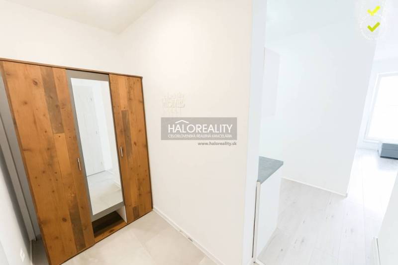 A wardrobe with a wooden decor in a studio apartment with light-colored walls.