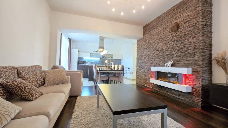 Interior of a 3-room apartment with a fireplace, wood-patterned flooring, and a comfortable sofa set.