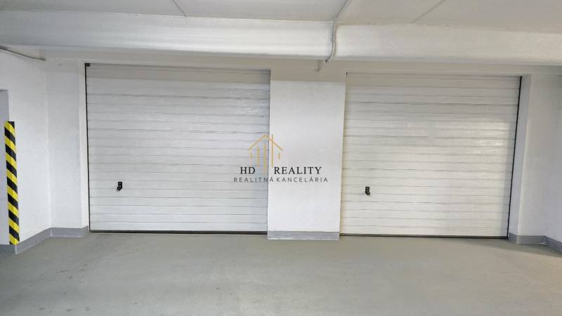Garage doors in an enclosed space, white walls, safety markings.