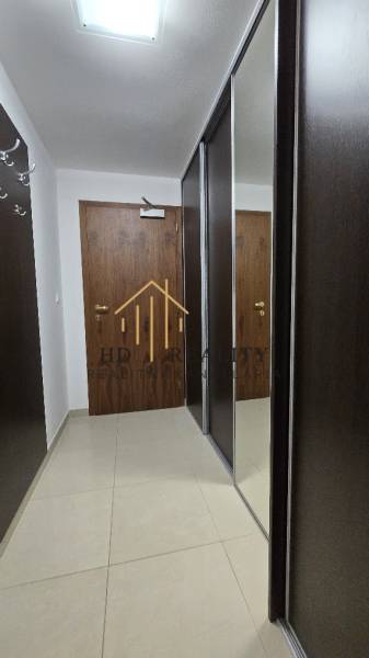 A hallway in a 3-room apartment with a mirrored wardrobe and plain-colored tiles.