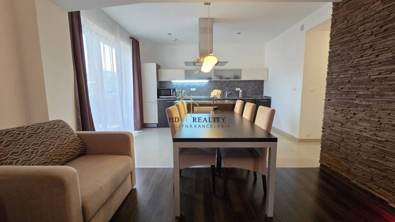 A spacious kitchen with a dining area and a wooden decor floor in a 3-room apartment.