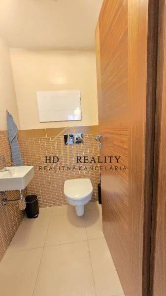 A bathroom in a 3-room apartment with a wood-patterned floor and a wall-mounted sink.