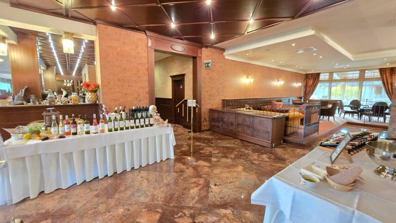 A restaurant with wines, a table with food, wooden decor, and well-lit seating.